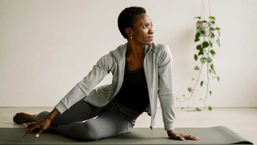 Woman performing a barre leg stretch on a mat in a bright studio with potted plant